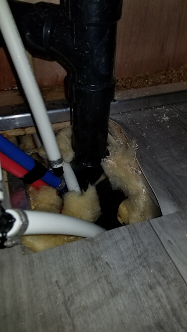 Picture of the wet wall and delaminate floor from the defective leaking PEX pipe in the storage area of a new Keystone Montana.